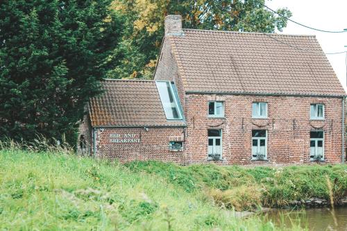 an old brick house on the side of a river at Hoeve Westdijk in Oostkamp
