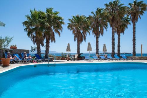 a swimming pool with palm trees and chairs at Paros Philoxenia in Chrissi Akti