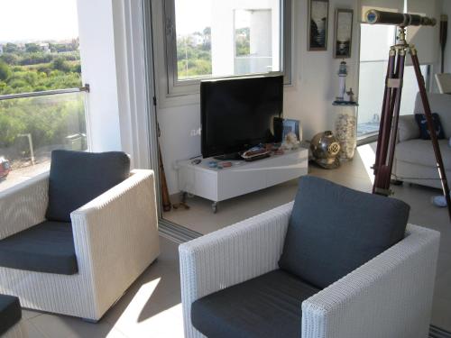 sala de estar con 2 sillas y TV de pantalla plana en Trident Beach Apartment en Protaras