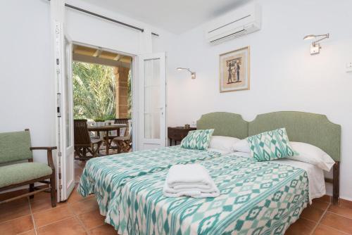 a bedroom with a bed with a green and white blanket at Villa Herdain in Alcudia