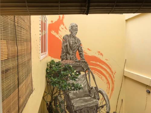 a statue of a man in a wheelchair painted on a wall at Hotel La Java Bleue in Kampot