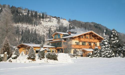 a large wooden building with snow on the ground at Gästehaus Trixl in Zell am See