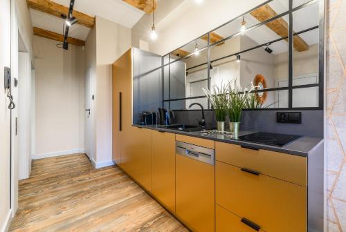 a kitchen with orange cabinets and wood floors at Piernikowe Apartamenty in Toruń