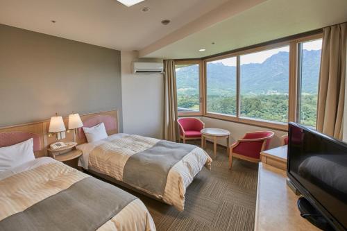a hotel room with two beds and a flat screen tv at Myogi Green Hotel in Tomioka