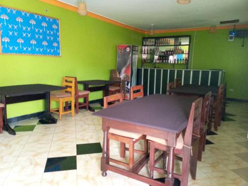 um restaurante com mesas e cadeiras e uma parede verde em Sipi Traveller's Lodge em Kapchorwa