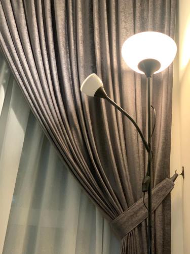 a floor lamp in front of a curtain at Relaxed Family Staycation, Pool View w WIFI n Netflix in Bangi