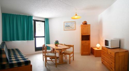 un salon avec une table à manger et une télévision dans l'établissement Village vacances du Haut-Bréda aux 7 Laux, à La Ferrière