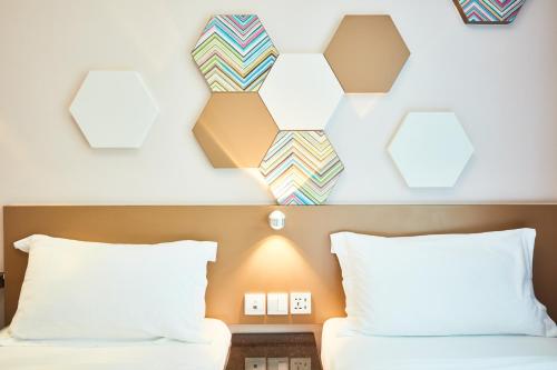 a bedroom with two beds and a wall with mirrors at ibis budget Singapore Imperial in Singapore