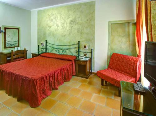 a bedroom with a red bed and a chair at Hotel Residence Villa Rioddi in Volterra