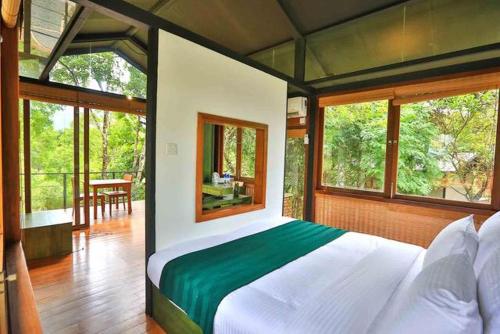 a bedroom with a large bed in a room with windows at Sennya Resorts in Belihul Oya