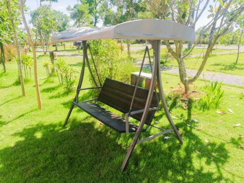 a swing with an umbrella in a park at Terrua Main Ten Villa Garden in Suan Phung