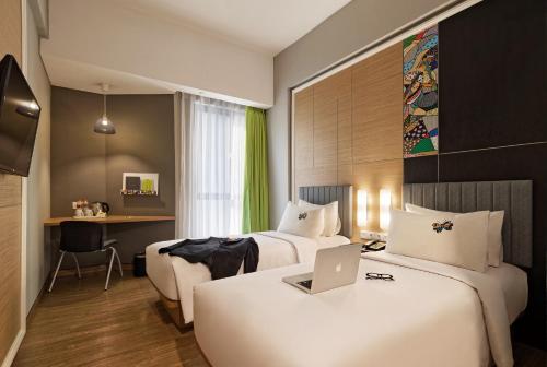 a hotel room with two beds and a laptop on a desk at MaxOne Platinum Hayam Wuruk in Jakarta