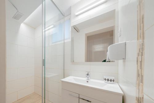 a white bathroom with a sink and a mirror at Apartments in Villa Olimp in Ljubljana