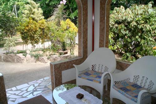a porch with white chairs and a table and a window at Rising Sun Guesthouse in La Digue