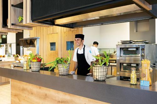 a man in a kitchen with plants on a counter at Cyprotel Faliraki in Faliraki
