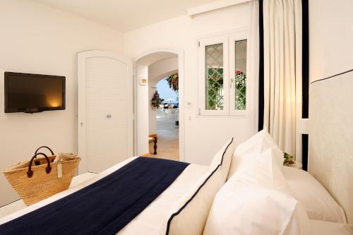a white bedroom with a bed and a television at Le Calette N.5 in Cefalù