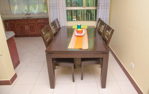 a wooden table with chairs and a plate with a cup on it at Sunset Paradise Holidays Homes in Shanzu