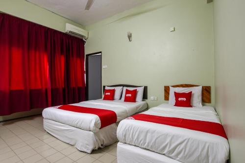 two beds in a hotel room with red pillows at OYO 89549 Casavilla Hotel (city Centre) Taiping in Taiping