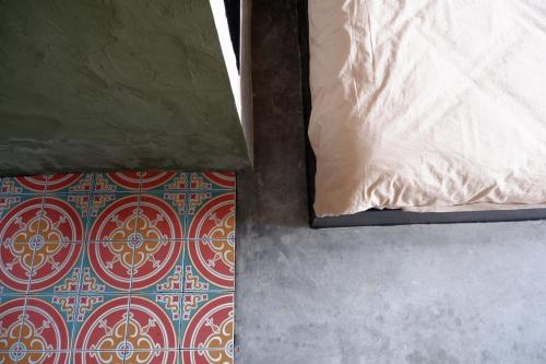 a bed with a pillow and a floor with a carpet at 88 Fine Hotel @ Suratthani Airport in Surat Thani