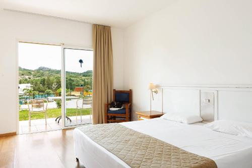 a bedroom with a large white bed and a balcony at Cyprotel Faliraki in Faliraki