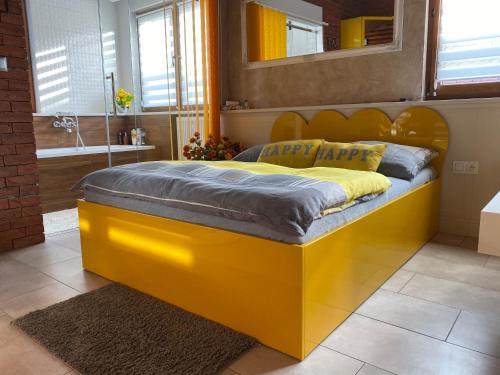 a large yellow bed in a room with a bathroom at Klinkierowy Apartament z wanną dla Dwojga in Gniezno