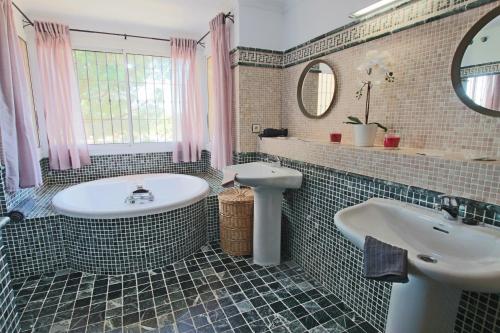 ein Badezimmer mit einer Badewanne, einem Waschbecken und einem Spiegel in der Unterkunft TESS Villa La Favorita in Alhaurín de la Torre