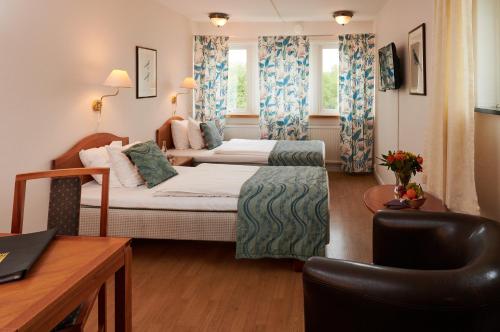um quarto de hotel com duas camas e uma secretária em Hotel Fars Hatt by Dialog Hotels em Kungälv