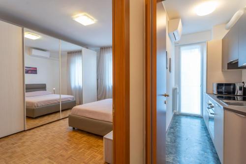 una camera con letto e una cucina con specchio di Udine Palazzo d'Aronco Modern Apartment a Udine