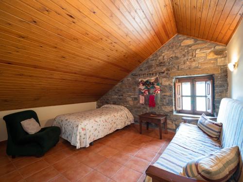 um quarto no sótão com uma cama e uma parede de pedra em Casa Coronas em El Pueyo de Araguás