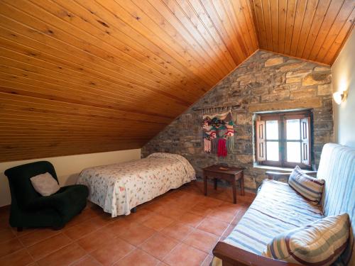una camera mansardata con letto e parete in pietra di Casa Coronas a El Pueyo de Araguás