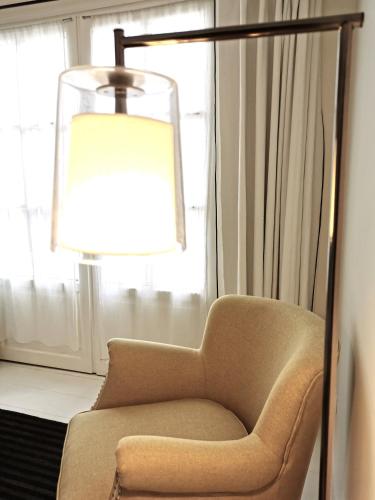a chair and a lamp in a room with a window at Le Clos Saint-Martin Hôtel & Spa in Saint-Martin-de-Ré