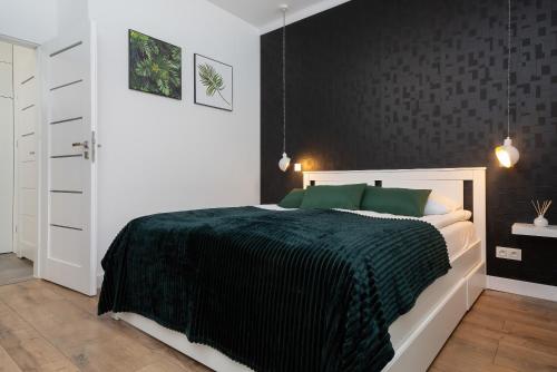 a bedroom with a bed with a black wall at Apartments Rzeczypospolitej by Renters Prestige in Warsaw
