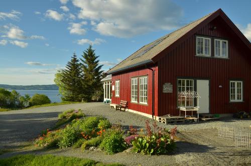 un granero rojo con un banco y flores delante de él en Klostergården Bed & Breakfast, en Tautra