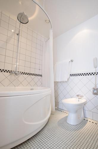 a white bathroom with a tub and a toilet at Pädaste Manor in Pädaste
