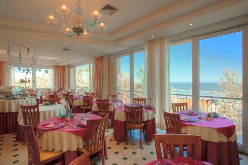 una sala da pranzo con tavoli, sedie e finestre di Hotel Nordic a Bellaria-Igea Marina