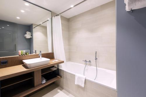 a bathroom with a tub, sink and shower at Golden Tulip Saint Malo– Le Grand Bé in Saint Malo