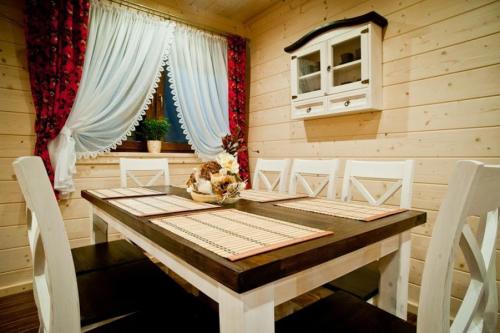 a dining room with a wooden table and white chairs at Domek Deluxe Resort Willa Adrian in Zakopane