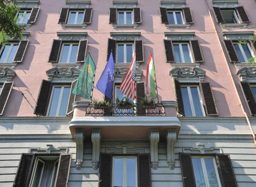 un bâtiment avec trois drapeaux sur un balcon dans l'établissement Hotel Mecenate Palace, à Rome