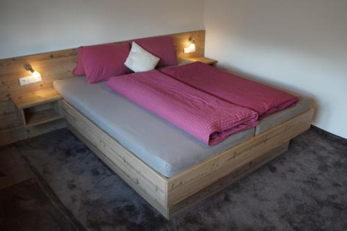 a bedroom with a wooden bed with pink sheets at Pferdehof Bachegg in Tobadill
