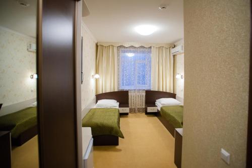 a hotel room with two beds and a window at Mereke Hotel in Ustʼ-Kamenogorsk