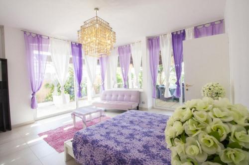 a bedroom with purple curtains and a bed and a chandelier at tenuta cotriero in Marina di Mancaversa