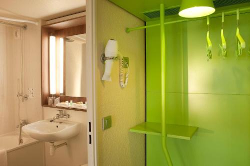 La salle de bains verte est pourvue d'un lavabo et d'une douche. dans l'établissement Campanile Epône, à Épône