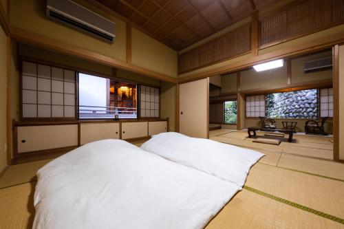 宿坊 端場坊｜Temple Hotel Habanobo في Minobu: غرفة نوم بسرير أبيض في غرفة بها نوافذ