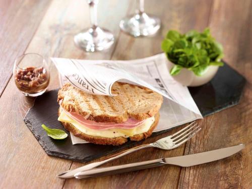 a sandwich on a black plate with a fork and knife at ibis Bayonne Centre in Bayonne