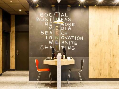a table with two chairs and a sign on a wall at Hotel Ibis Krakow Centrum in Kraków