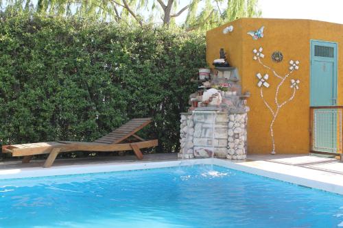 Una piscina con un banco al lado de una casa. en Cabañas El Naranjo, en San Rafael