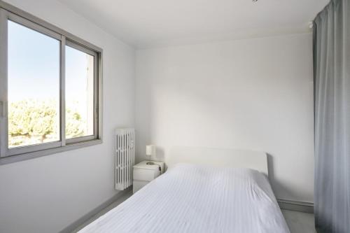 une chambre blanche avec un lit et une fenêtre dans l'établissement Appartement Soleil d'Antibes - Welkeys, à Antibes