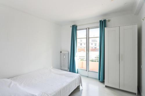Un dormitorio blanco con una cama y una ventana grande. en Appartement Soleil d'Antibes - Welkeys, en Antibes