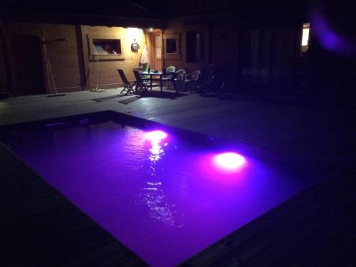- une piscine avec des lumières violettes dans une pièce sombre dans l'établissement Chalet aux 3 biches, à Mieussy