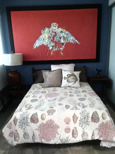 a bedroom with a bed with a large painting above it at Isla Verde By The Beach Guest House in San Juan